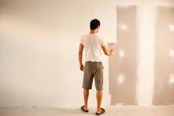 A Man Painting A Wall With White Color